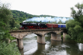 Sonderzug von einer Dampflok gezogen überquert die Saale (Eisenbahnbrücke) neben der Brücke der Einheit